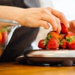 woman putting strawberry on scales