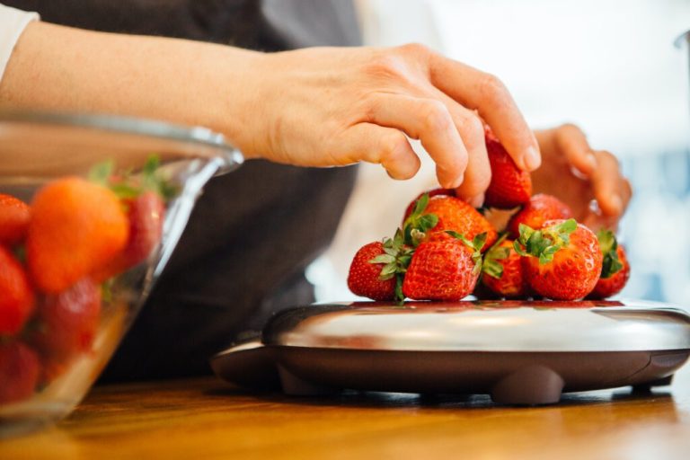 woman putting strawberry on scales